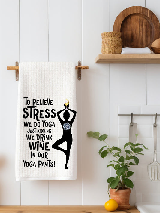 White kitchen towel with humorous yoga and wine quote hanging on a wooden towel rack in a modern kitchen