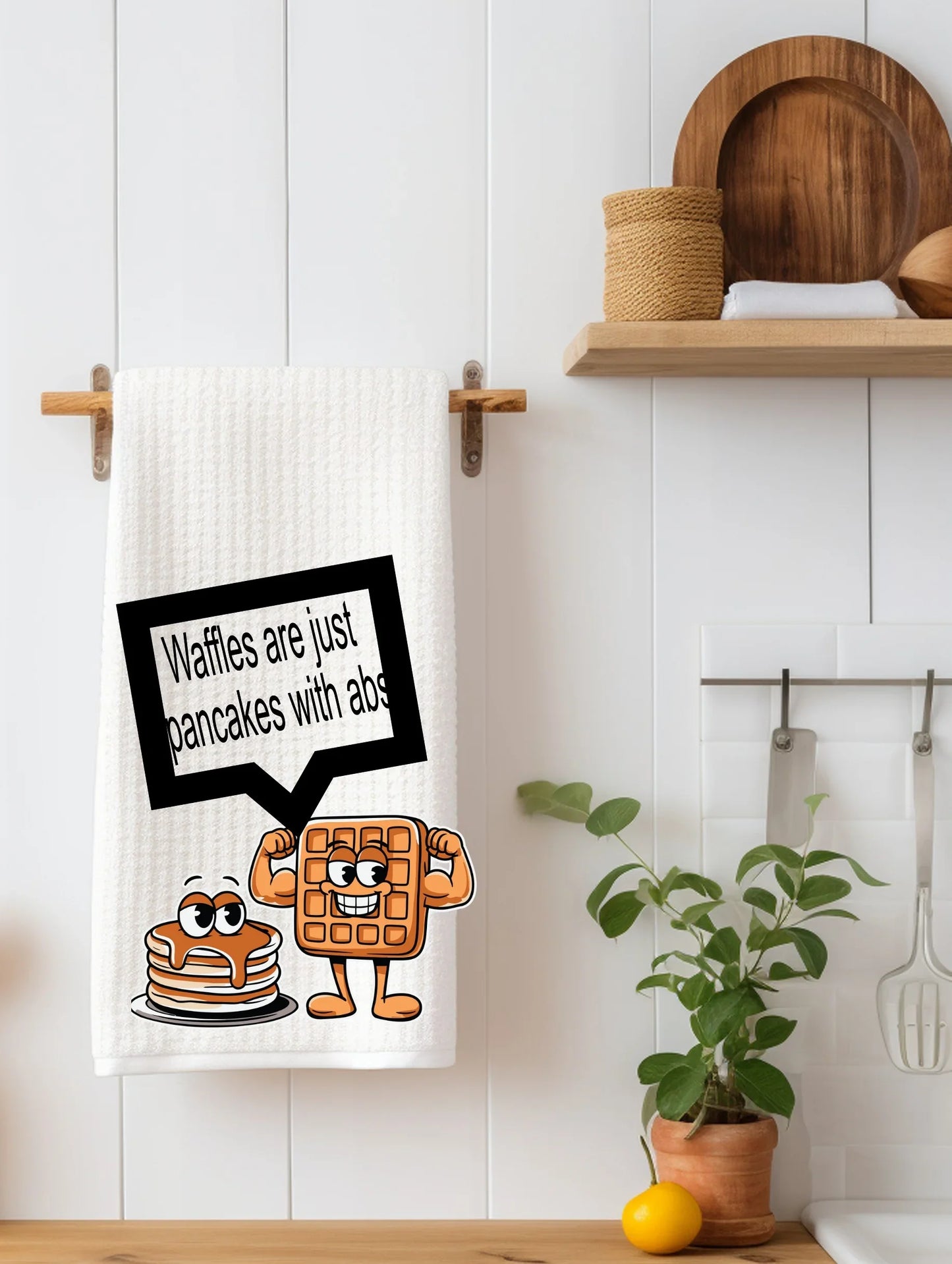 White kitchen towel with cartoon waffle and pancake saying waffles are just pancakes with abs